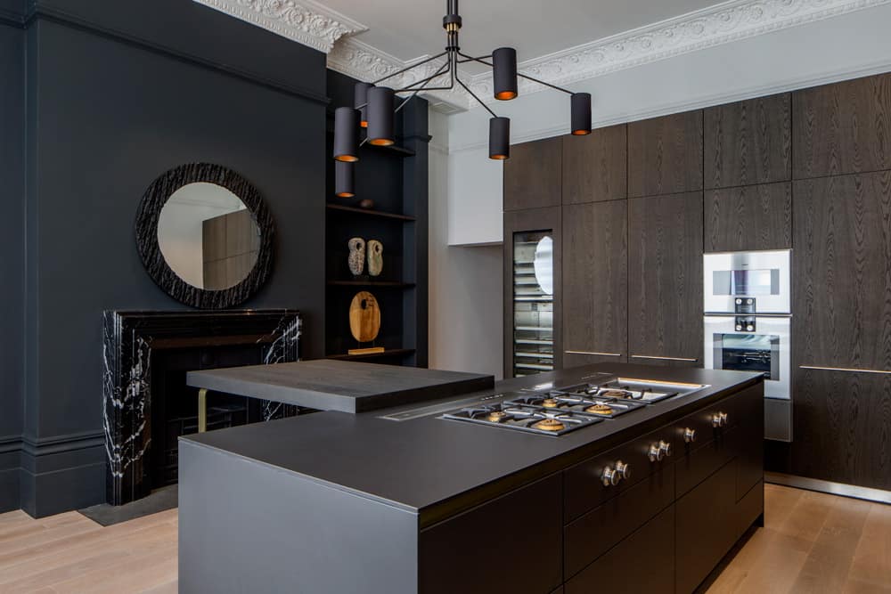 kitchen featuring dark brown kitchen island and dark grey wall with fireplace and round mirror