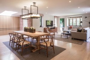 open plan dining area with 8-seater oak dining table and wishbone chairs and rectangular pendant light with candles