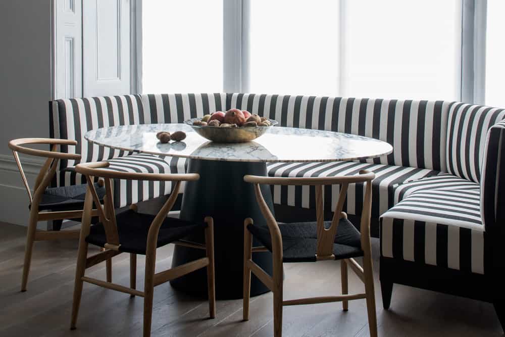 black and white kitchen banquette dining area in bay window with wishbone chairs