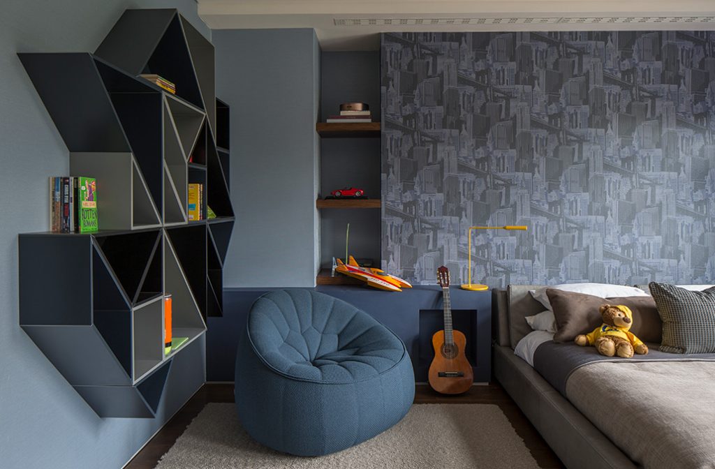 blue boys bedroom with patterned wallpaper and geometric shelving