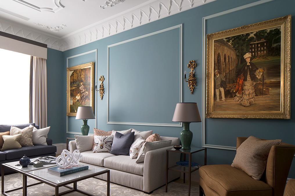 elegant living room with blue walls and gold framed oil paintings