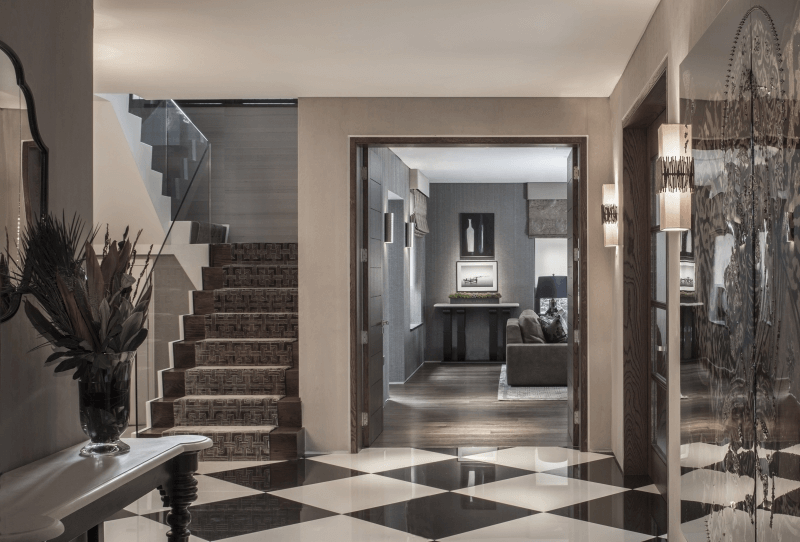 Luxurious entrance hall with black and white chequered floor tiles, bespoke console table and view through to living room vignette