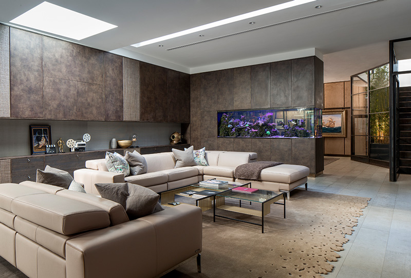 basement living room with bespoke fitted joinery, modern sofas and beige rug