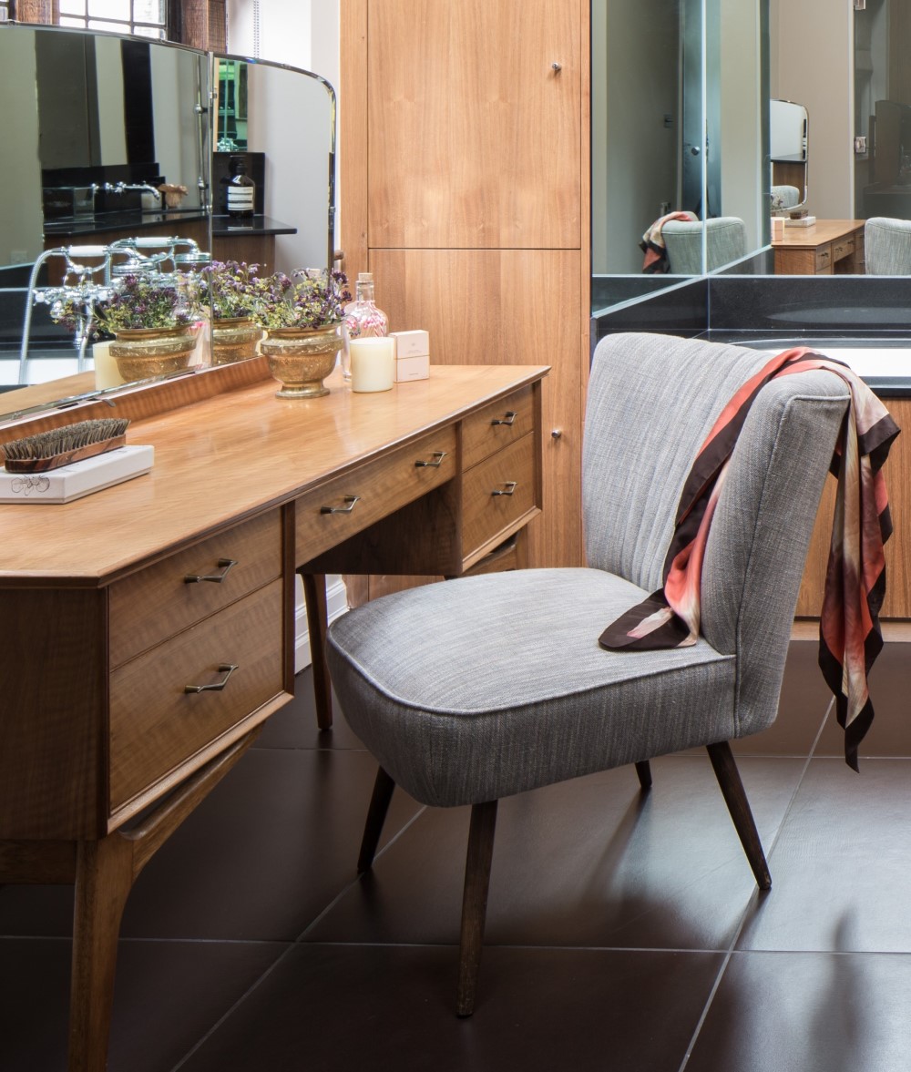 Dressing room with grey chair and wooden vanity
