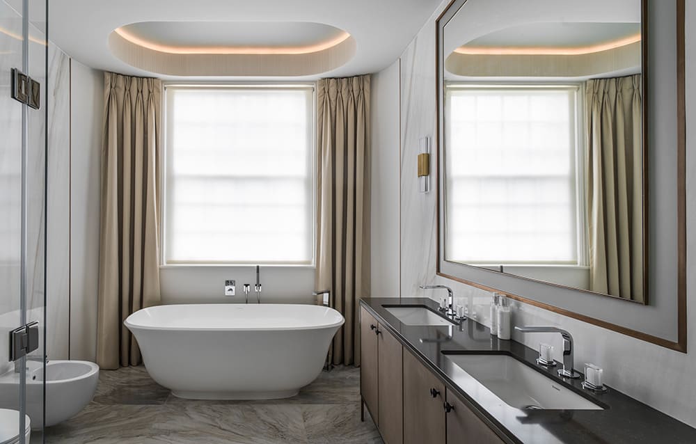 elegant master bathroom with large freestanding bath, sash window with floor to ceiling curtains and coffered ceiling with LED lights