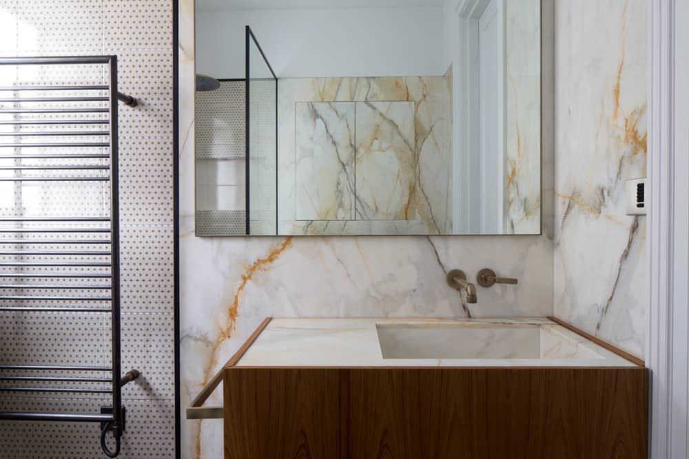 the vanity basin in this industrial bathroom is constructed from calacatta marble encased in a teak unit to complement the gold veining of the marble