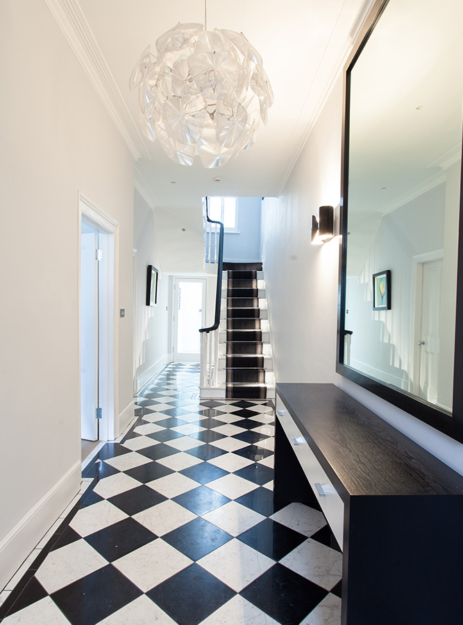 black and white entrance hallway with chequered floor and pendant light